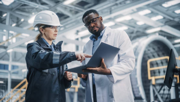 white female and black male aerospace engineers discuss manufacturing project